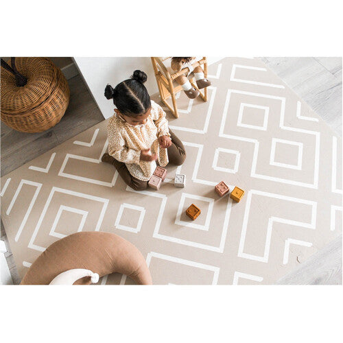 Een kind speelt met blokken op de eeveve foam speelmat met beige en wit geometrisch patroon.