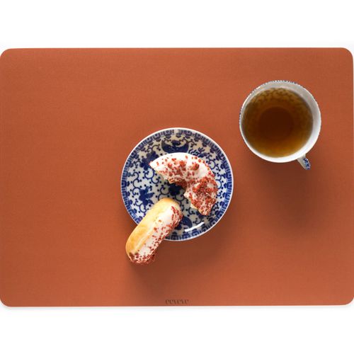 eeveve placemat in roestkleur met een bordje gebak en een kop thee.