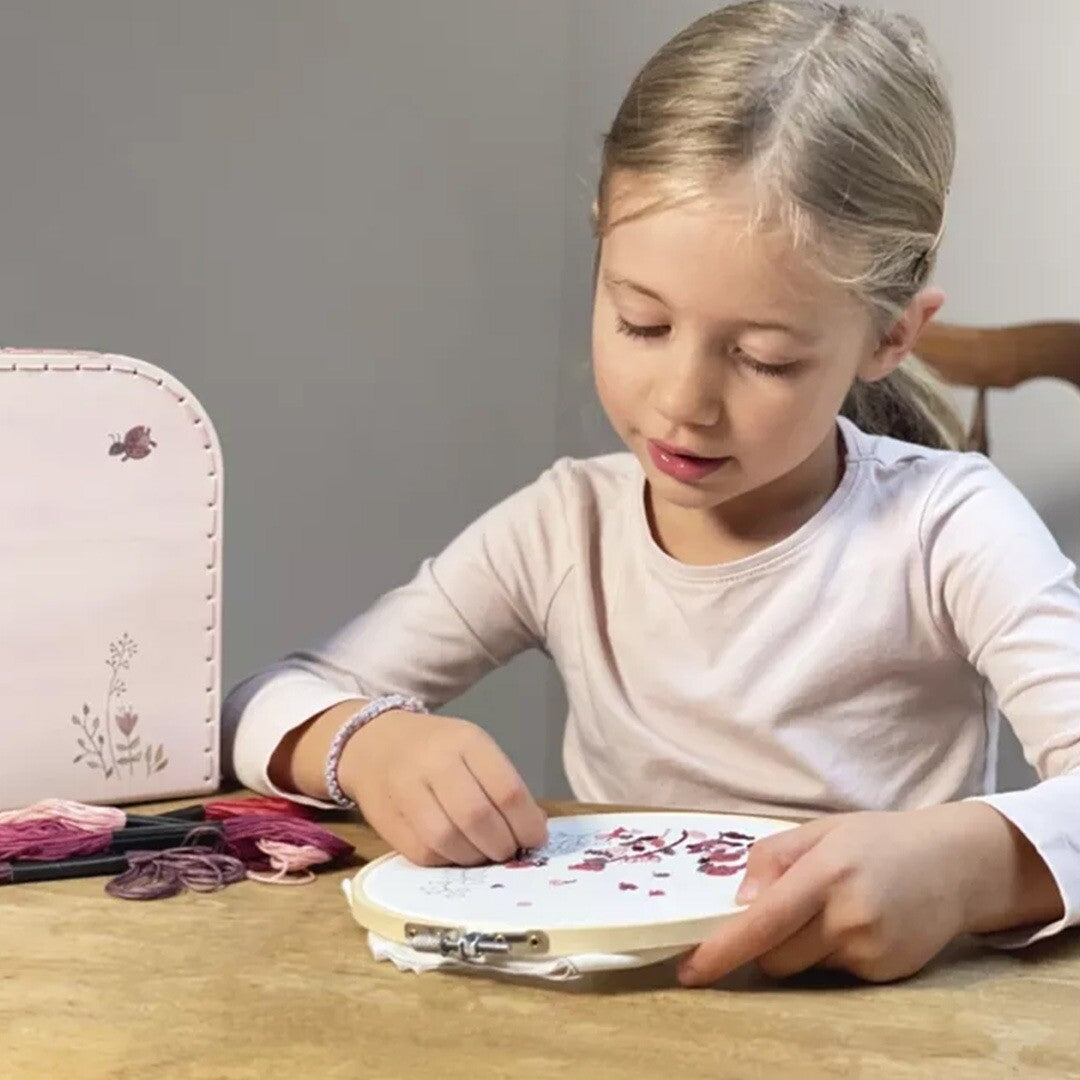 Een meisje borduurt een gebloemd patroon met het Egmont Toys borduurpakket.