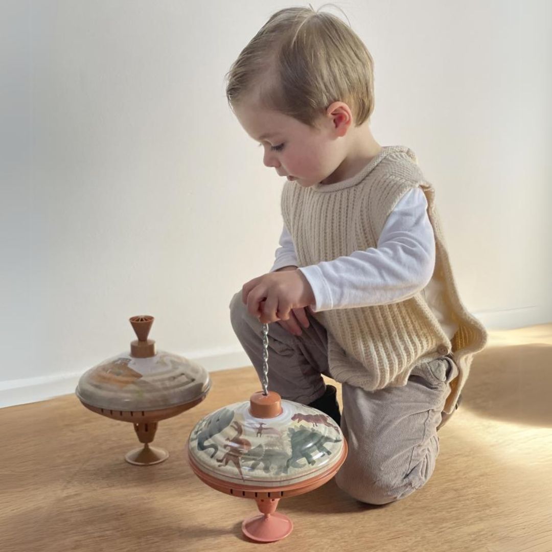 Een kind speelt met twee Egmont Toys metalen bromtollen met Ark van Noah thema.