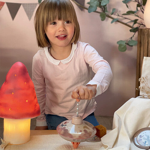 Een lachend meisje speelt met de Egmont Toys metalen bromtol.