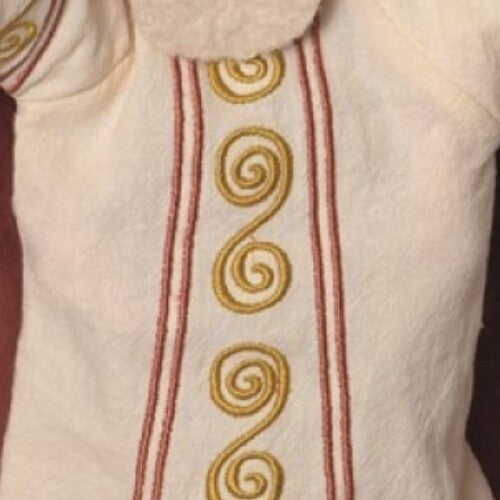 Detail van de witte mantel van de handpop met gouden spiraal- en rode streepborduursels.