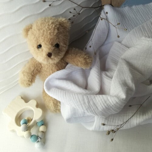 Egmont Toys knuffelbeer Morris, een bruine pluchen teddybeer voor baby's, naast een witte doek en een houten rammelaar.