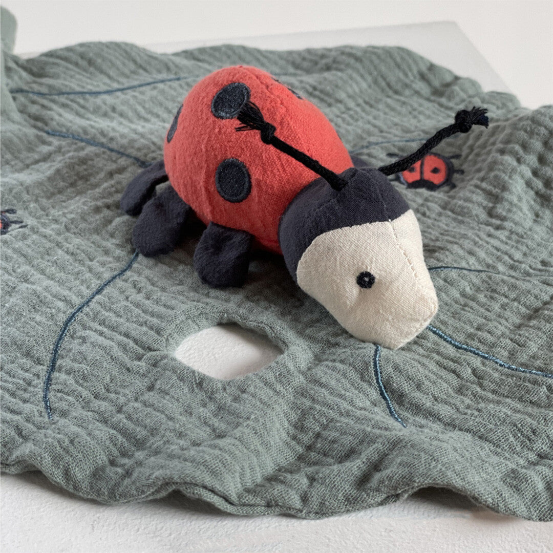 Detail van het Egmont Toys babyspeelgoed lieveheersbeestje op de grijze knuffeldoek met bladpatroon.