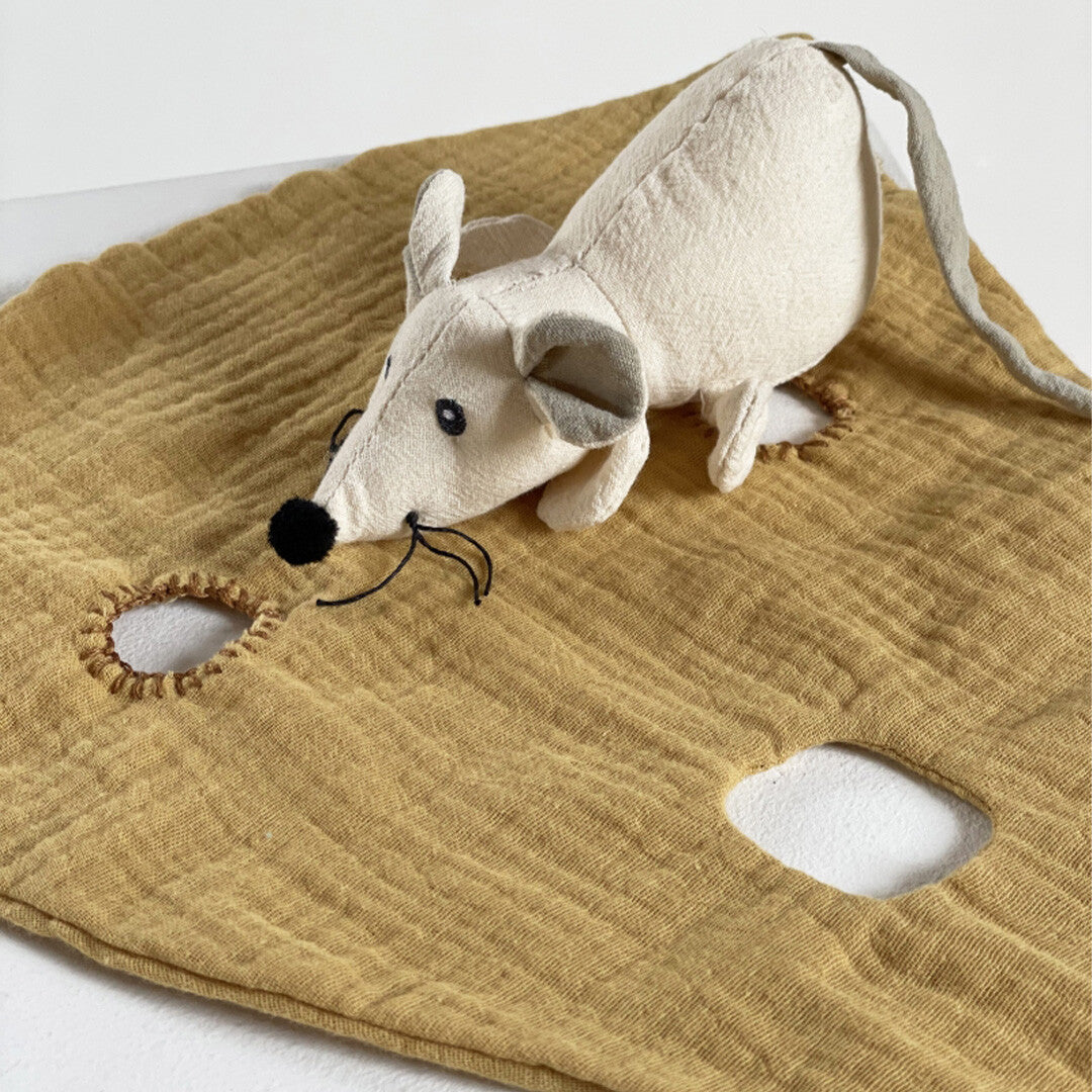 Detailfoto van de witte pluchen muis op de gele, kaasvormige knuffeldoek.
