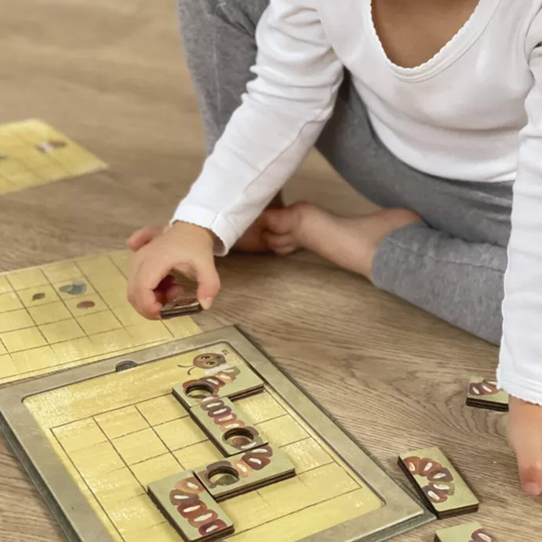 Een kind speelt op de grond met het magnetische rupsenspel.