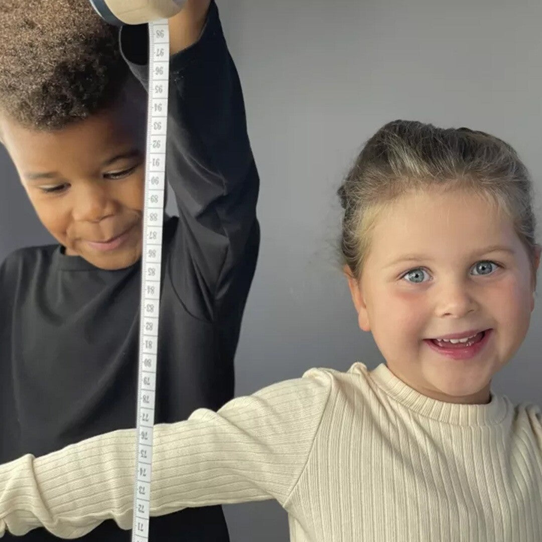 Twee lachende kinderen spelen met het Egmont Toys meetlint.