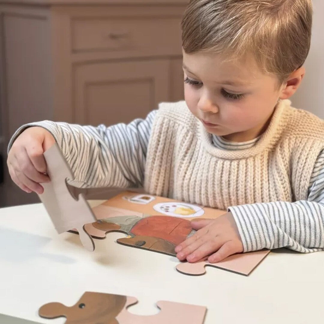Een jongetje legt een stukje van de Marcel kinderpuzzel met een beer aan tafel.