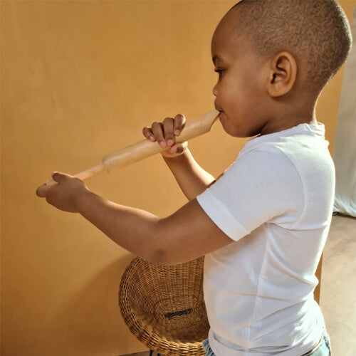 Een kind speelt op de Egmont Toys houten schuiffluit.