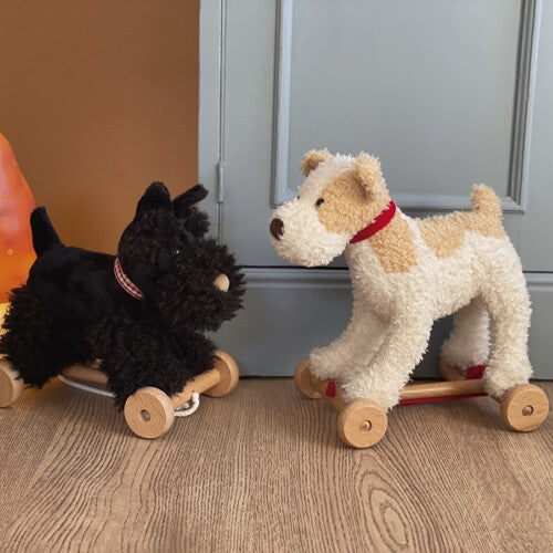 Twee Egmont Toys pluche trekfiguren honden, een beige met bruine vlekken en een zwarte, op een houten vloer.