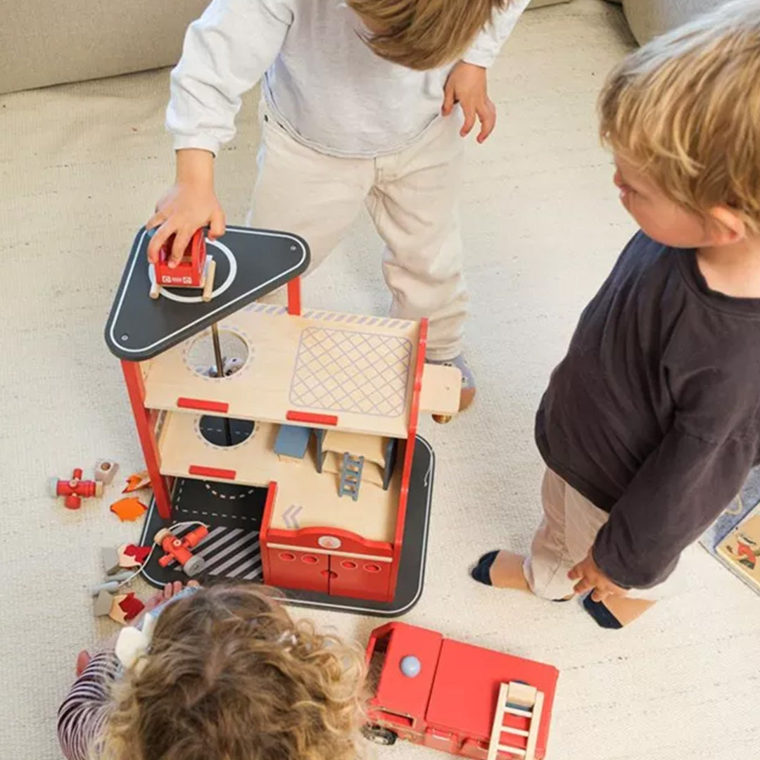 Twee kinderen spelen met de Egmont Toys houten brandweerkazerne en bijbehorende accessoires.