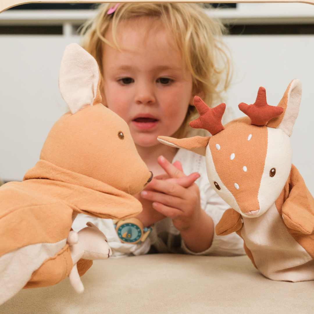 Een jong kind kijkt aandachtig naar een Egmont Toys handpop hertenkalf en een kangoeroe handpop.