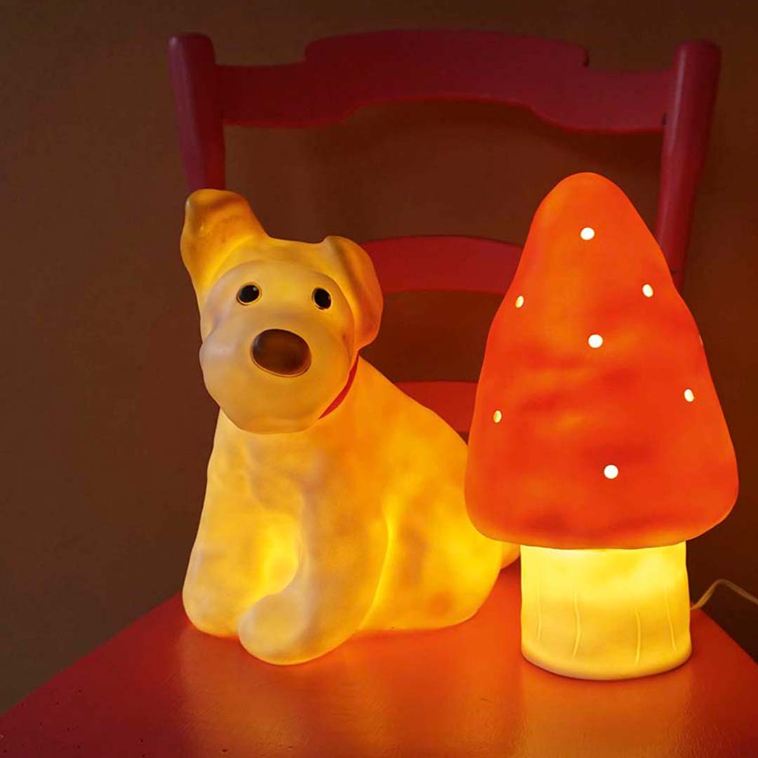 De Egmont Toys Heico hondenlamp staat brandend naast een rode paddenstoellamp op een rode stoel.