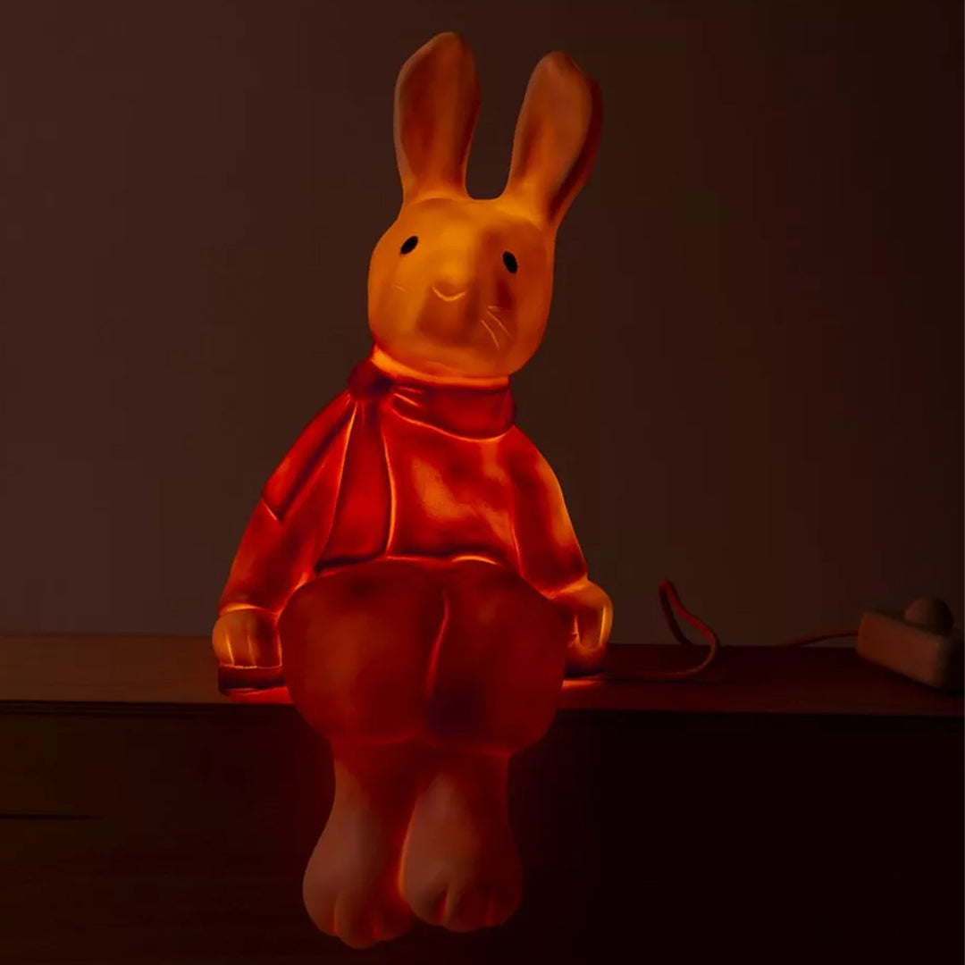 De Egmont Toys Heico lamp konijn Lenny gloeit oranje in een donkere kamer.
