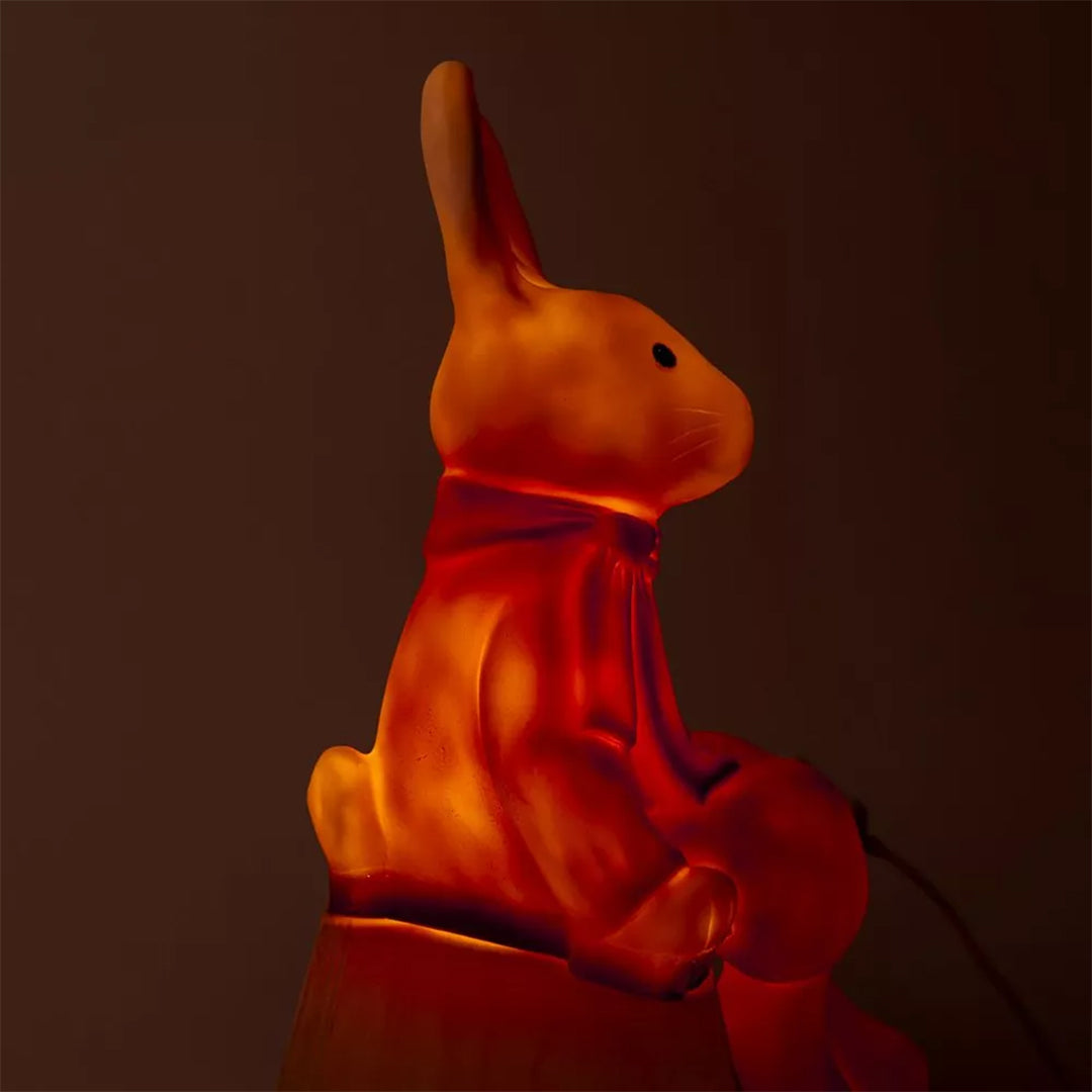 Zijaanzicht van de Egmont Toys Heico lamp konijn Lenny die oranje gloeit.