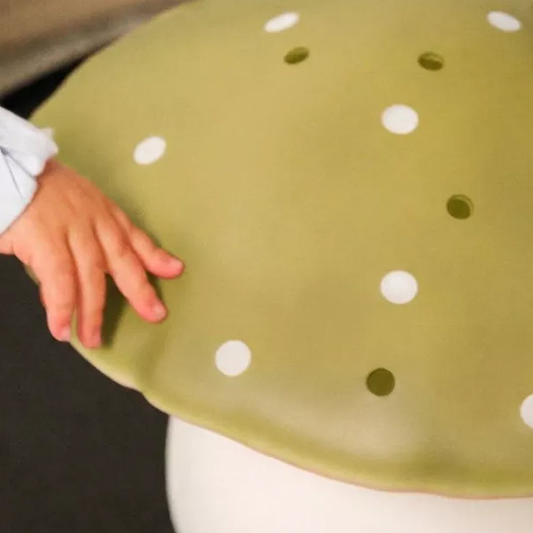 Een kinderhand raakt de lemon grass paddenstoelkap met witte stippen van de lamp aan.