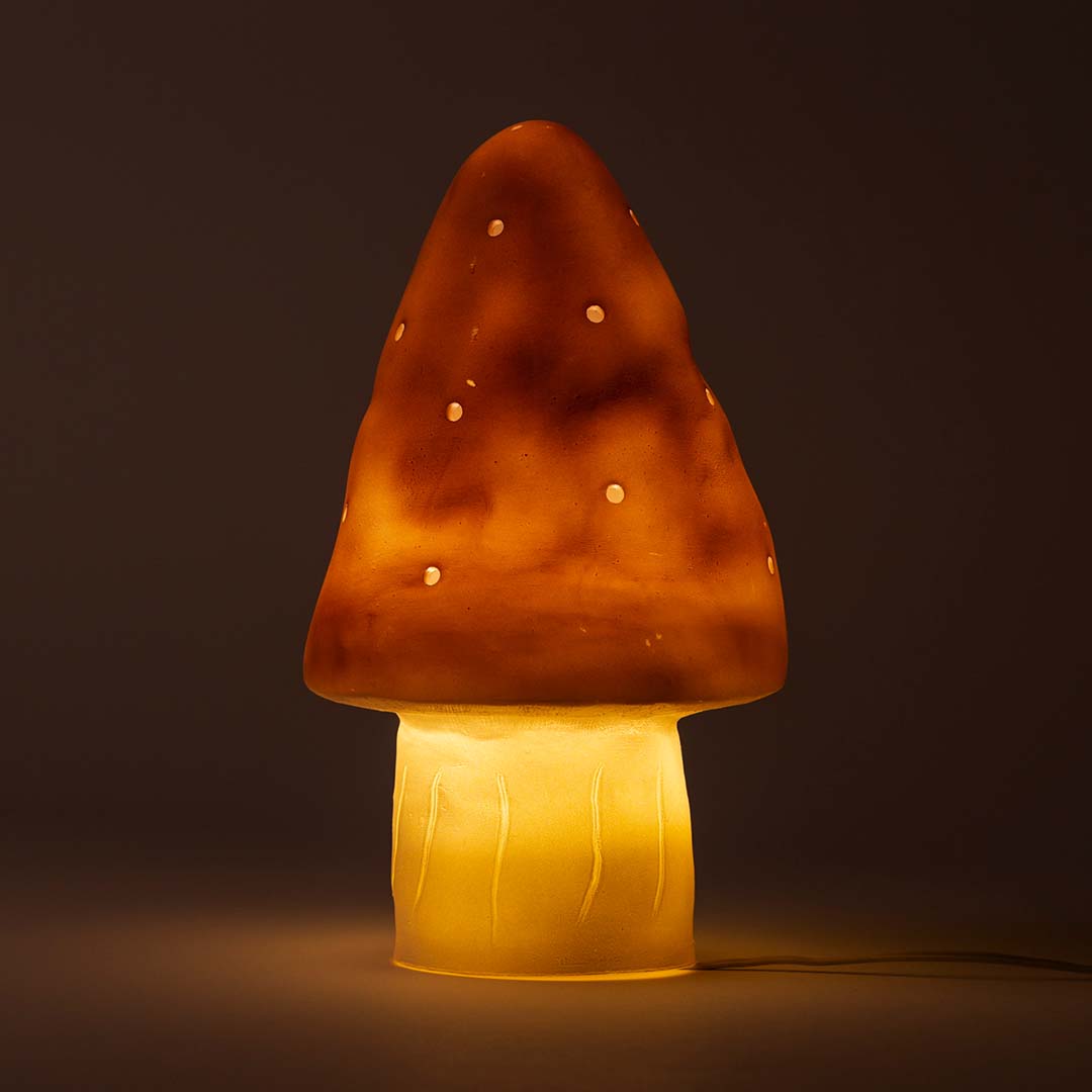 De paddenstoel nachtlamp brandt en geeft warm licht in een donkere omgeving.