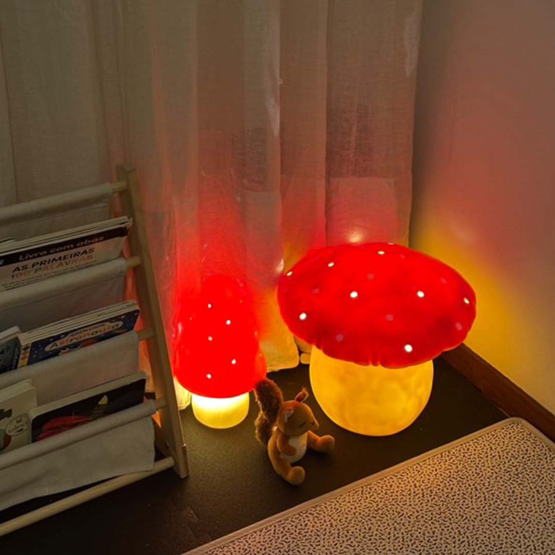Twee Egmont Toys vliegenzwam nachtlampen verlichten een kinderkamer naast een boekenrek en een knuffeleekhoorn.