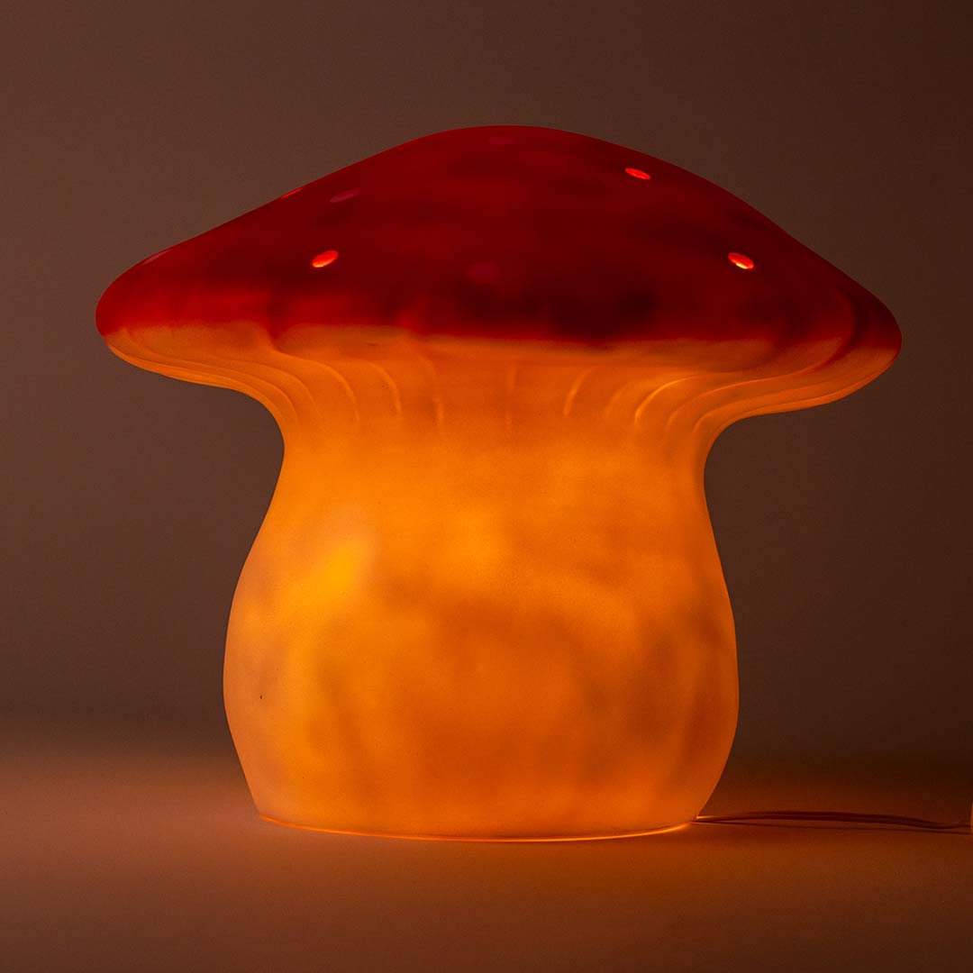 De Egmont Toys vliegenzwam nachtlamp is verlicht en geeft een warme oranje gloed.
