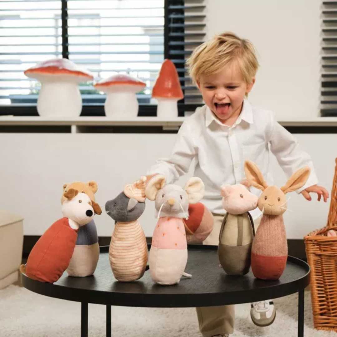 Een peuter lacht terwijl een van de Egmont Toys stoffen dieren kegels omvalt.