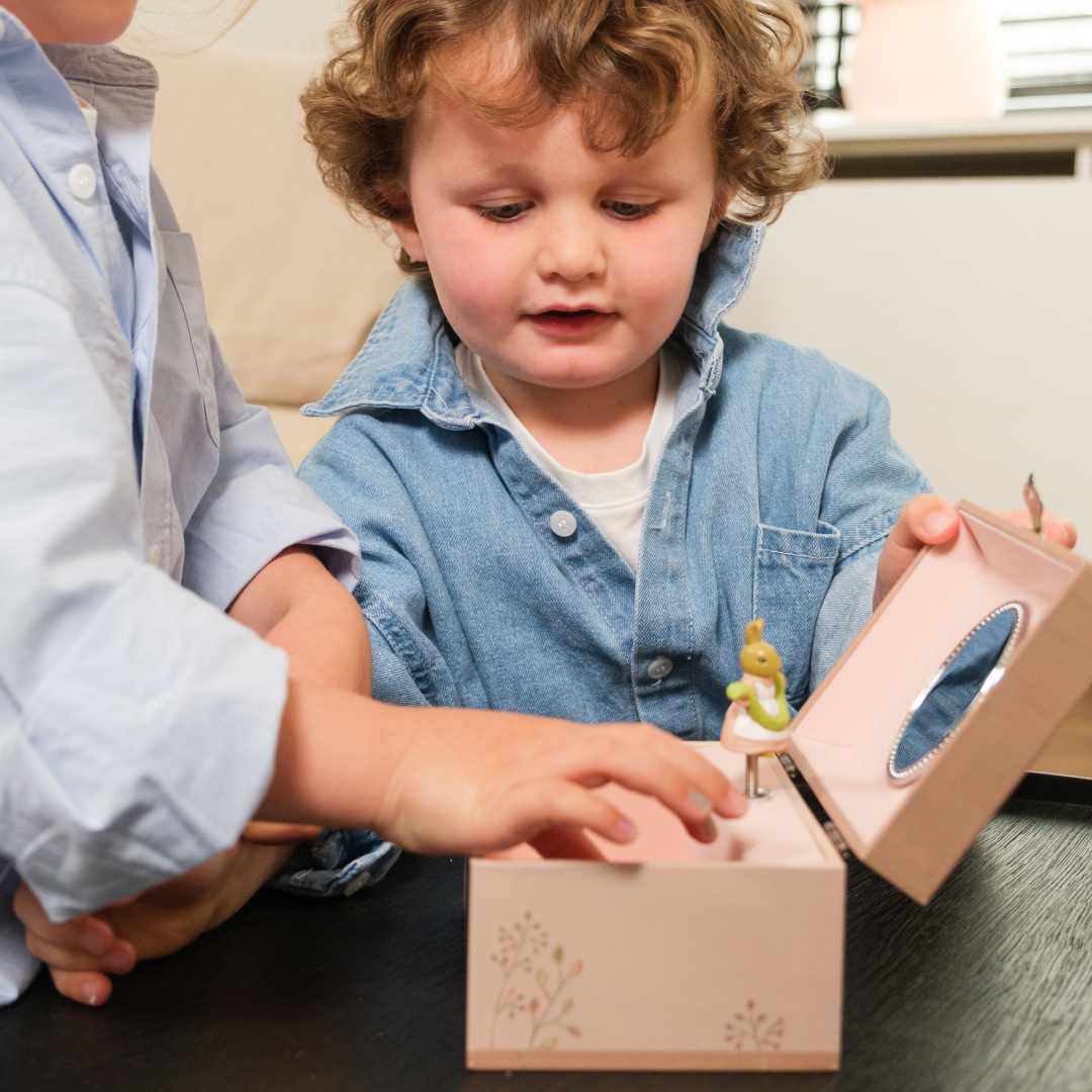 Een kind opent het Egmont Toys roze houten muziekdoosje met het dansende konijntje.