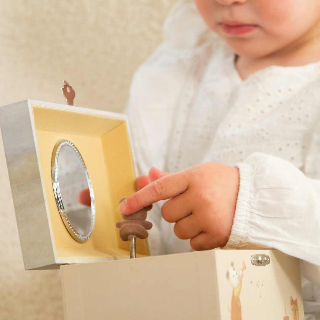 Een kinderhand raakt het dansende beertje aan in het open Egmont Toys houten muziekdoosje.