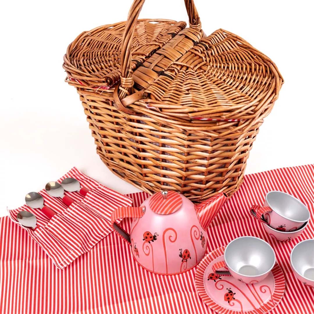 Egmont Toys speelgoed theeservies met roze lieveheersbeestjespatroon, inclusief theepot, kopjes en lepels, op een gestreepte doek naast een rieten picknickmand.