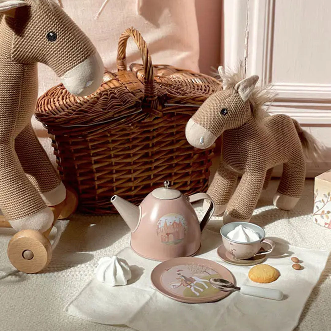 Egmont Toys theeservies met roze prinses-thema theepot en kopje, naast twee gebreide paardenspeeltjes en een rieten mand.