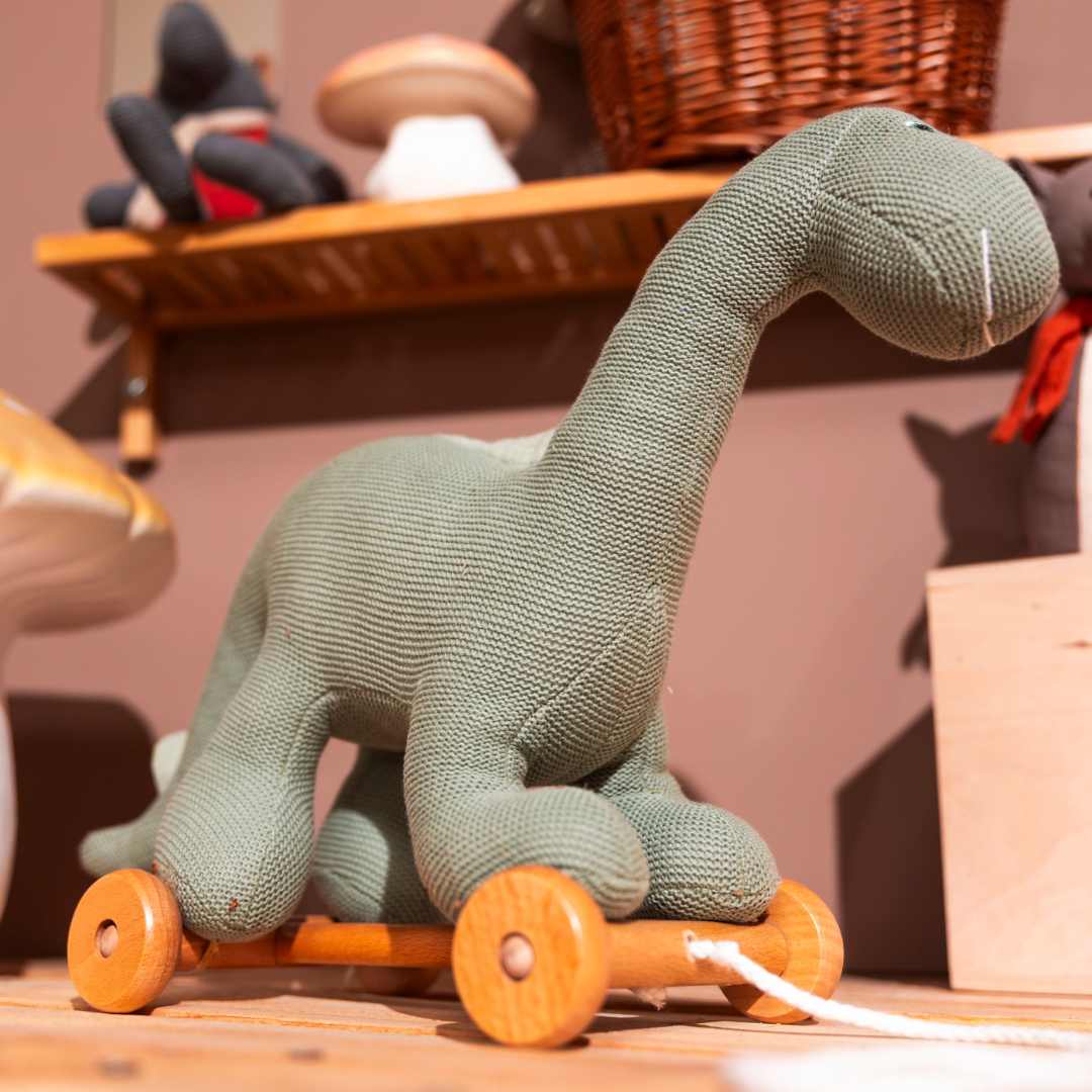 Egmont Toys groene gebreide dinosaurus Victor trekfiguur op een houten ondergrond.