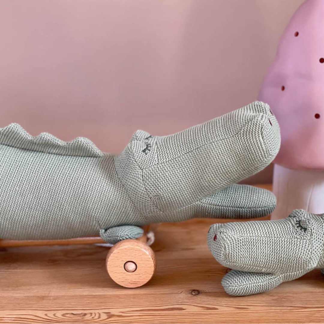 Close-up van de Egmont Toys groene gebreide krokodil trekfiguur met een kleinere knuffelkrokodil ernaast.