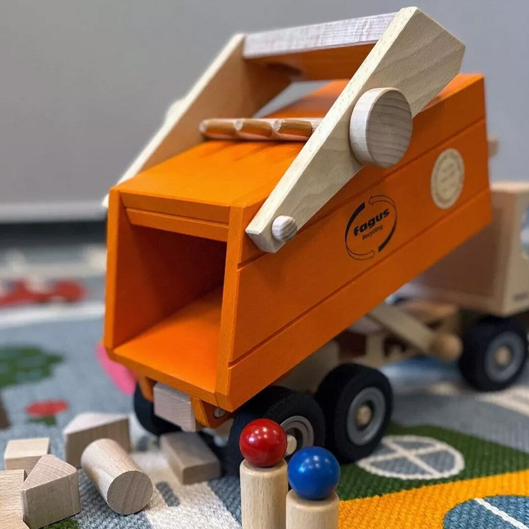 Fagus houten vuilniswagen met de oranje laadbak omhoog gekanteld op een speelkleed.