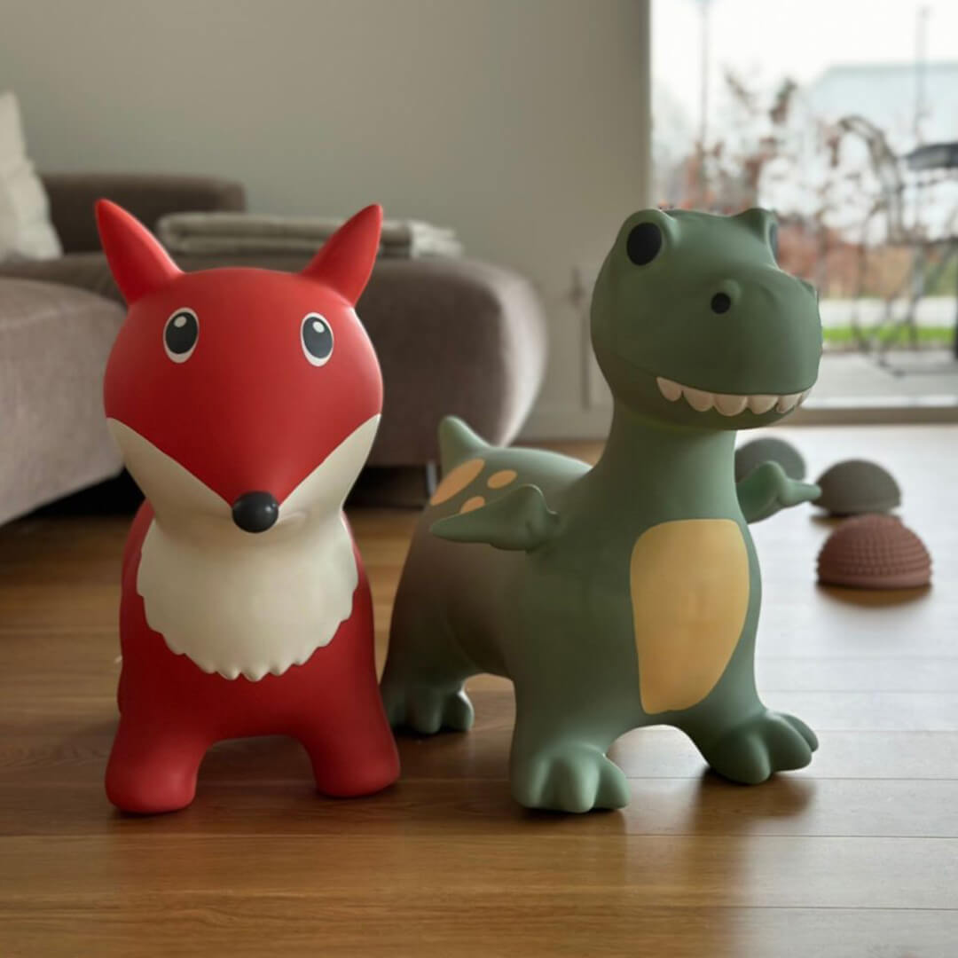 De find that hippo skippydier dino staat naast een rode vossen skippydier op een houten vloer.