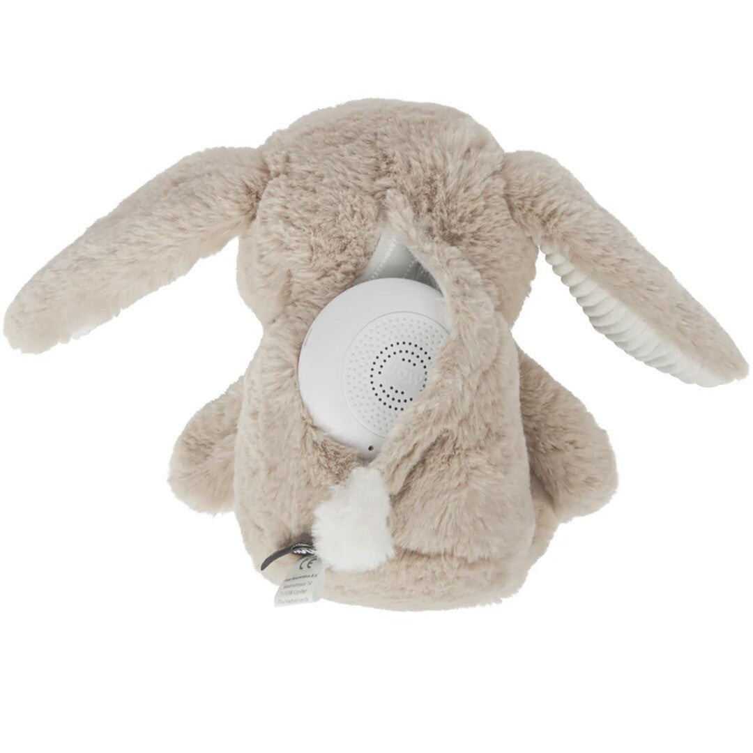 De achterkant van het bruine pluchen knuffelkonijn voor baby's, met het witte oplaadbare hartslagapparaat in een opening.