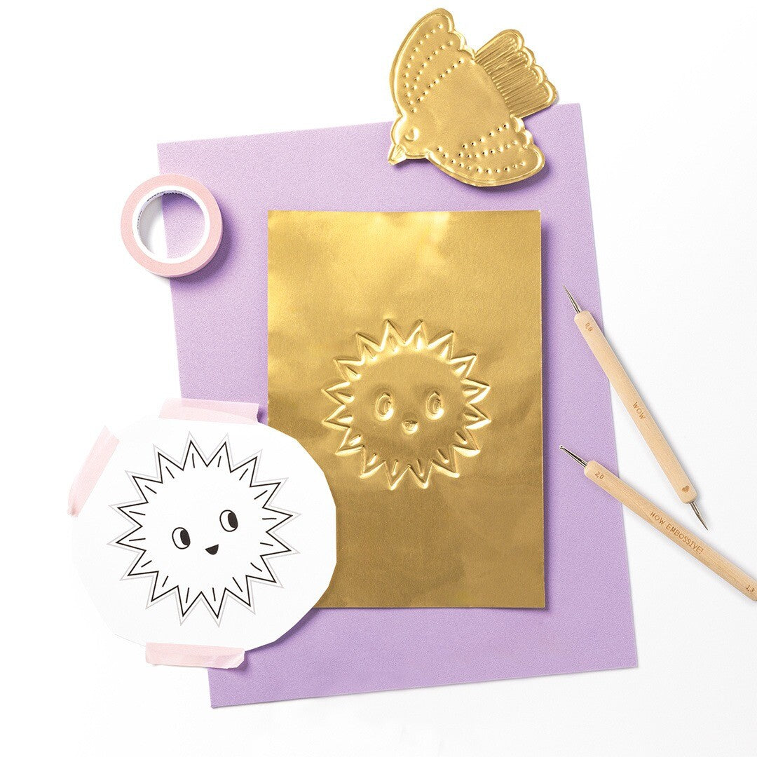 Een demonstratie van Folia embossing met pennen, inclusief een gouden zon en vogel op een paarse kaart.