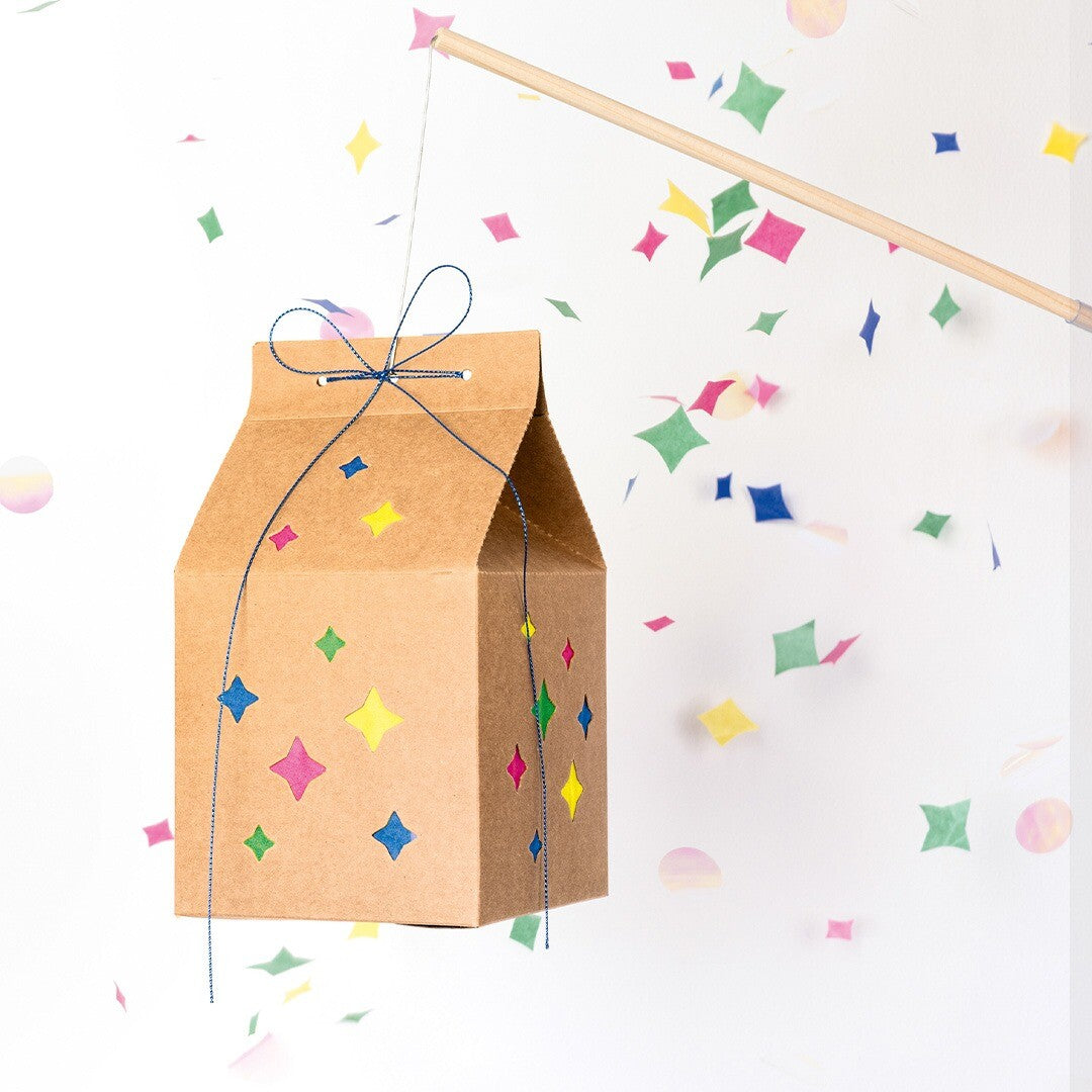Folia knutselset lantaarn met sterren hangend aan een stok, omringd door confetti.