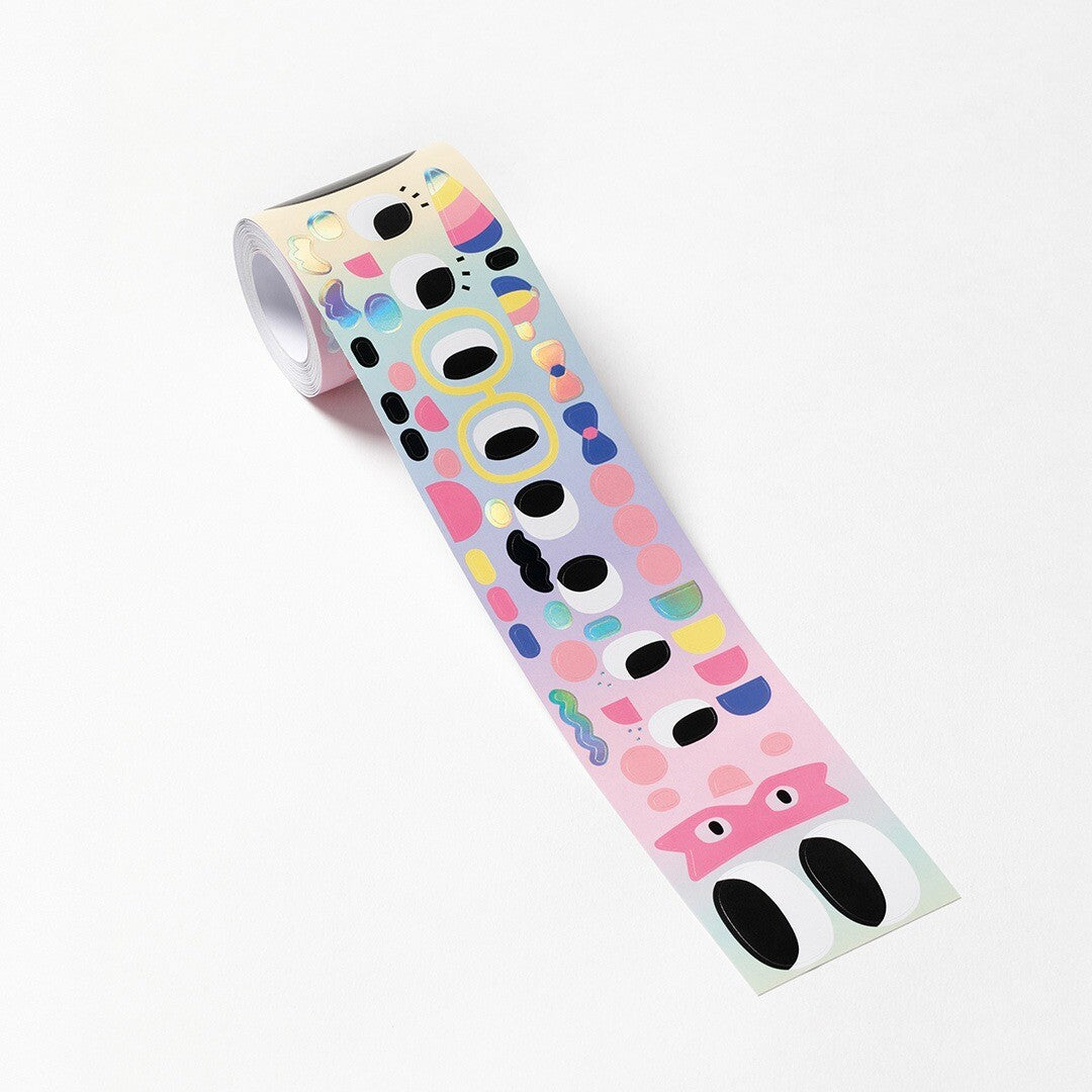Een Folia stickerrol met veelkleurige figuren en gezichtjes, deels afgerold op een witte ondergrond.