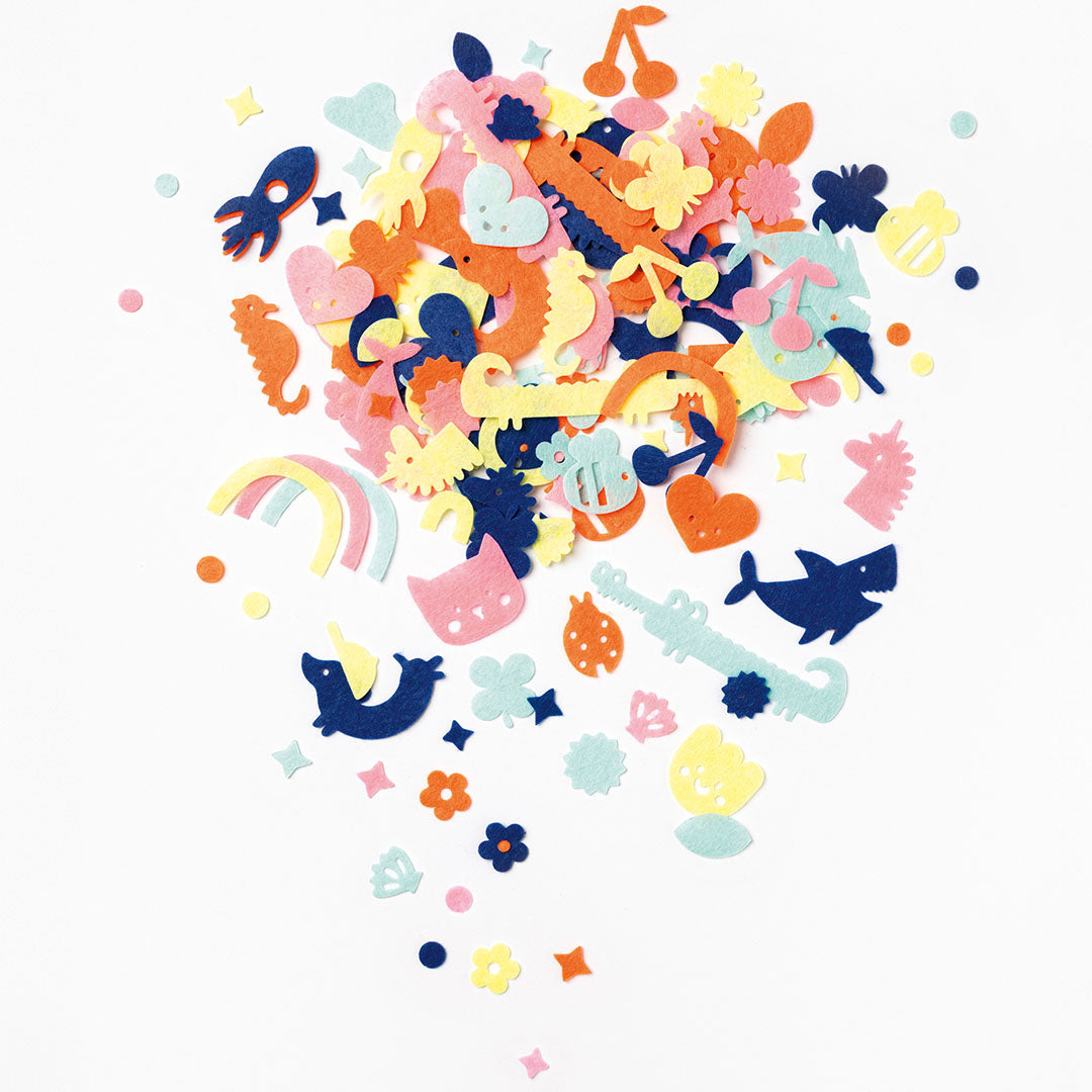 Een grote verzameling veelkleurige vilten vormpjes met diverse patronen zoals dieren, voertuigen, harten, bloemen en sterren.