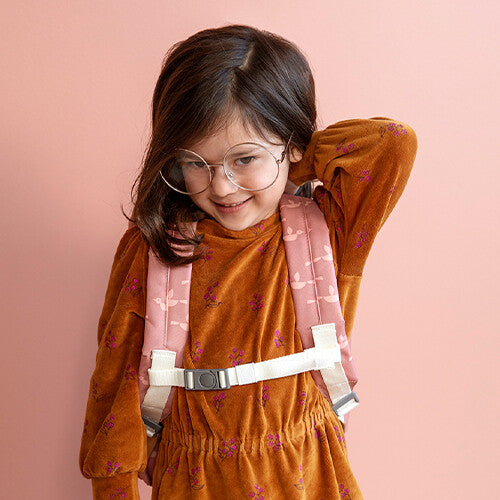 Meisje draagt een roze kinderrugzak met de Fresk borstriem.