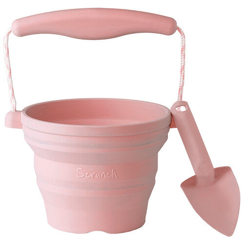 Een roze Scrunch opvouwbare siliconen emmer met schepje voor zandbakspeelgoed.