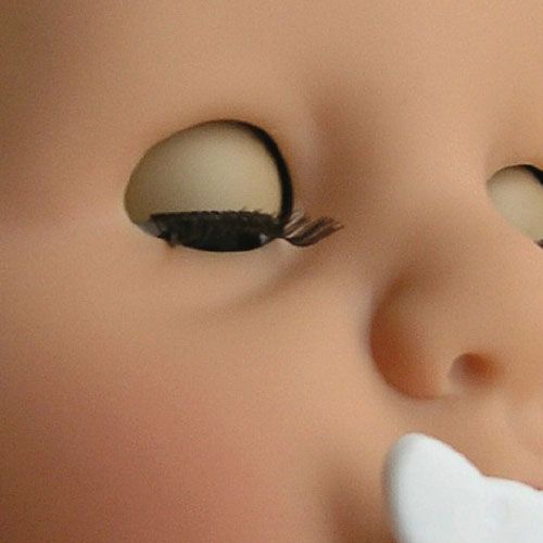 Close-up van het gezicht van de babypop met gesloten ogen en een witte speen.