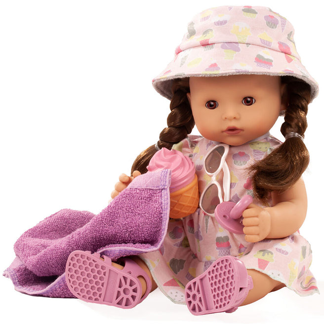 Götz babypop met bruine vlechten, roze jurk met ijsthema, roze hoedje, sandalen, handdoek en speelgoedijsje.