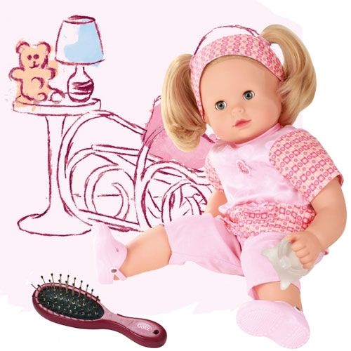 Gotz babypop Maxy Muffin zittend met een haarborstel en flesje, voor een getekende achtergrond van een kinderkamer.