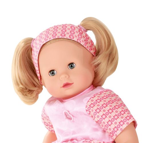 Close-up van het gezicht en de blonde pigtails van de Gotz babypop Maxy Muffin in een roze outfit.