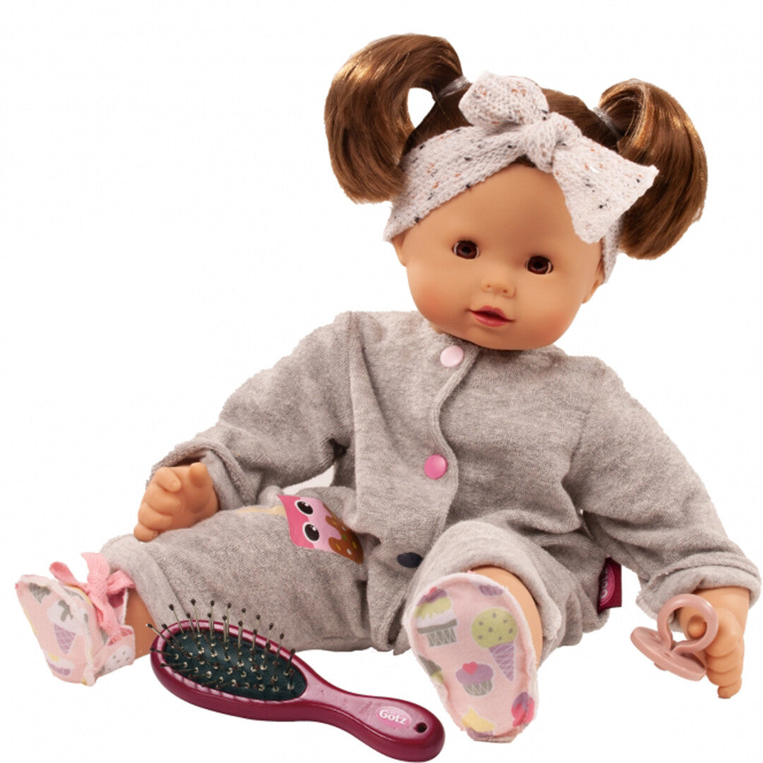Gotz babypop Maxy Muffin met bruine staartjes, een grijze jumpsuit met ijsjespatch en roze accessoires.