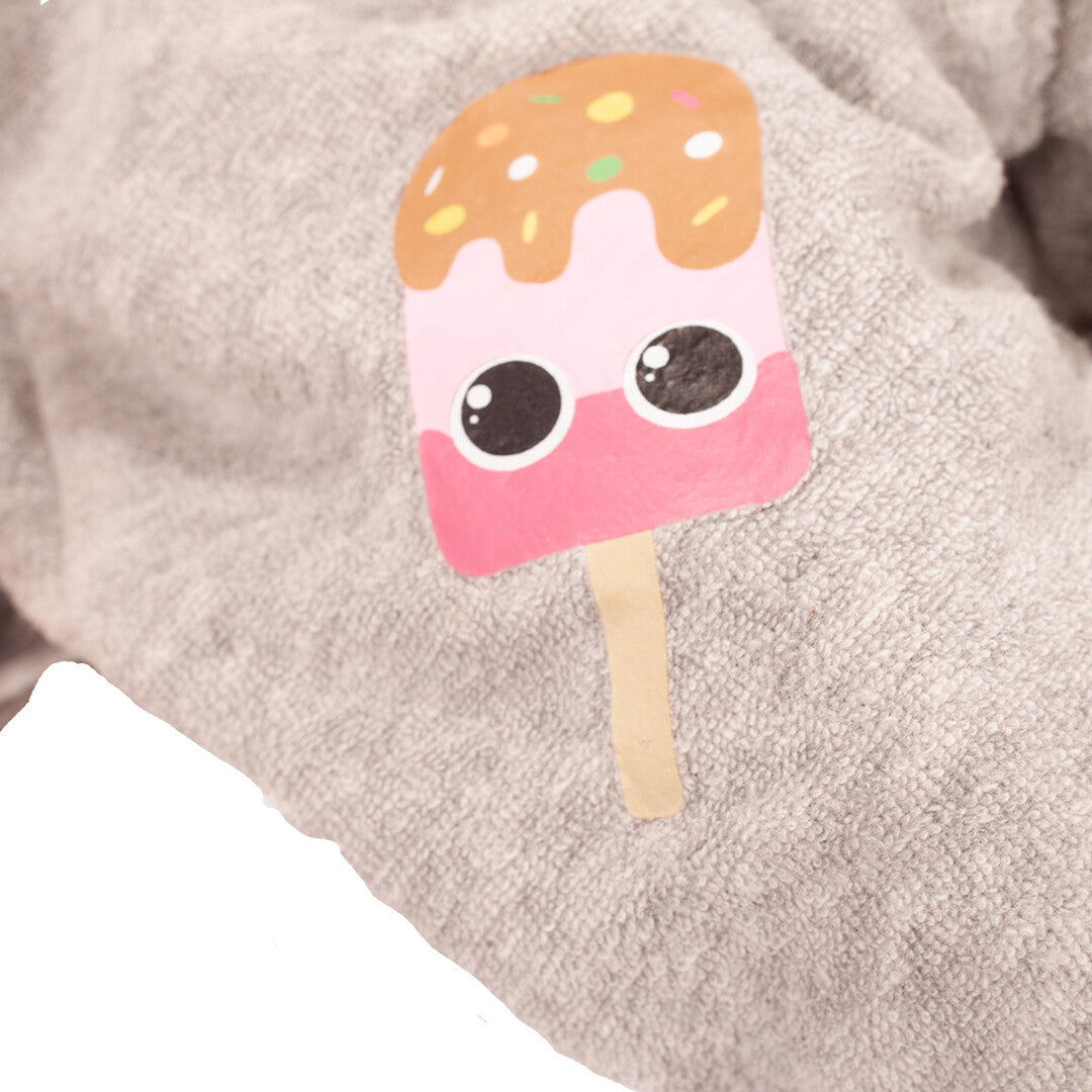 Detail van een roze ijsjespatch met ogen op de grijze jumpsuit van de babypop.