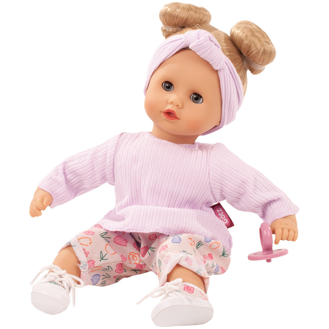 Gotz babypop Muffin Bliblablume zittend in paarse kleding met bloemenpatroon en een roze speen.