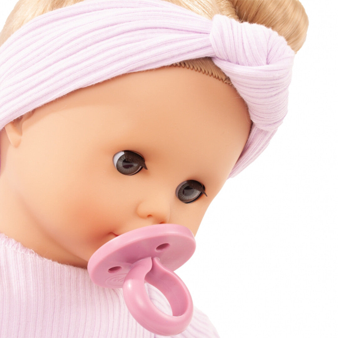Detailfoto van het gezicht van de Gotz babypop met een roze speen in de mond.