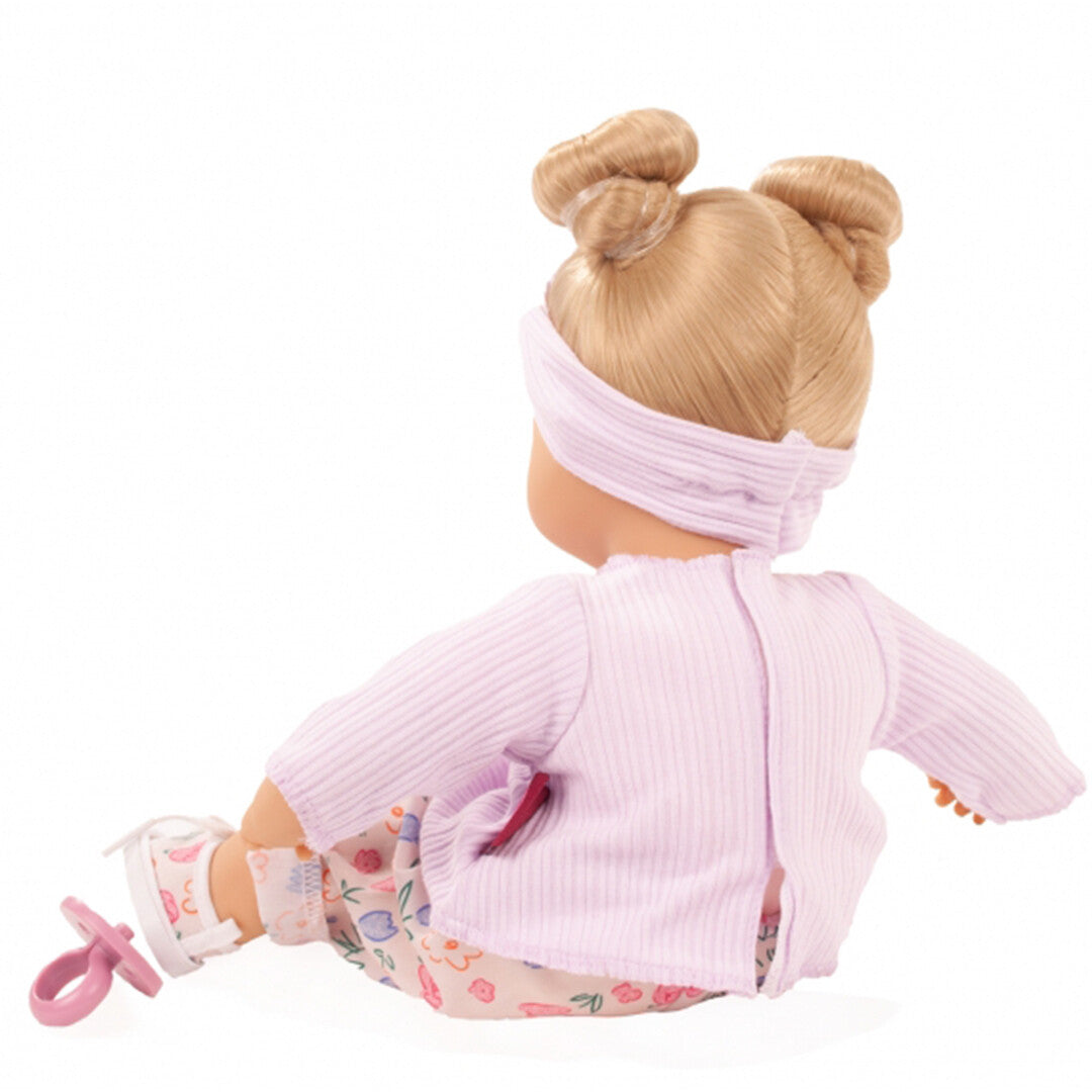 Achteraanzicht van de Gotz babypop in paarse kleding met bloemenpatroon.