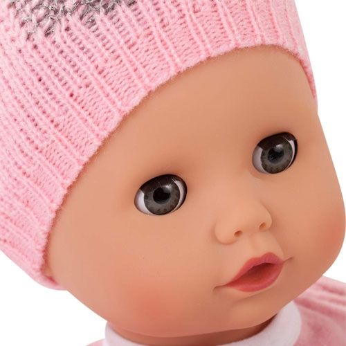Close-up van het gezicht van de babypop met grijze ogen en roze muts.