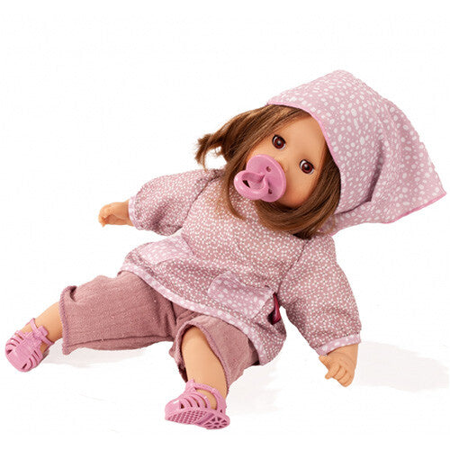 Götz babypop Muffin Soft Mood met bruin haar, roze kleding met stippen en roze sandalen, liggend met een roze speen in de mond.